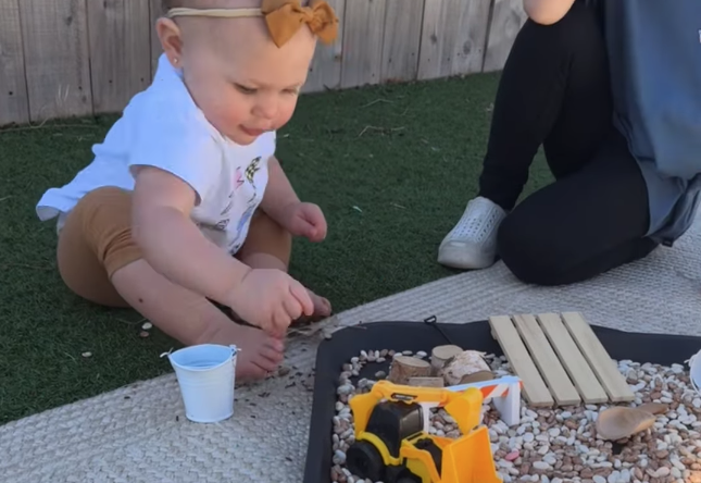 A baby sits in front of a construction sensory box at the Fort Worth indoor play space, the Play Pocket.
