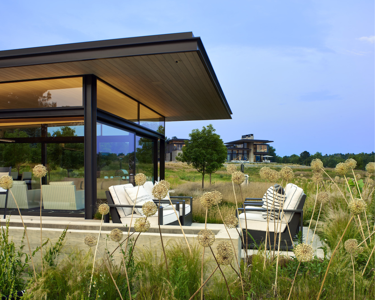 Modern glass pavilion with outdoor seating amidst a field, ideal for The Scout Guide exploration.