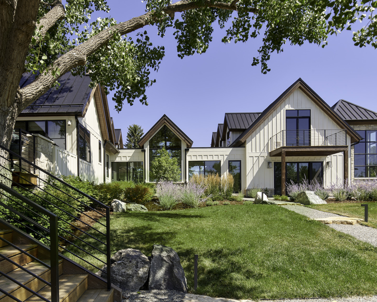 Modern farmhouse surrounded by lush greenery and trees under a clear sky, presented by The Scout Guide.